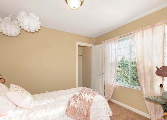 A bedroom with a bed, a window with curtains, and a chandelier at The Landing Apartments and Townhomes, Oregon, 97045