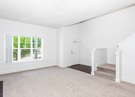 A living room with a staircase and a door at The Landing Apartments and Townhomes, Oregon, 97045