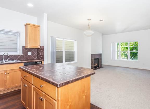 A kitchen with wooden cabinets and a brown countertop at The Landing Apartments and Townhomes, Oregon, 97045