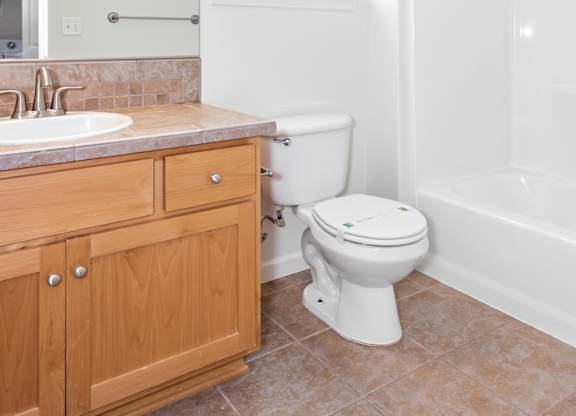 A white toilet sits in a bathroom next to a sink at The Landing Apartments and Townhomes, Oregon, 97045