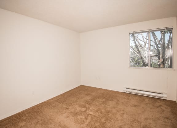 large bedroom with a  window and a carpeted floor at Todd Village Apartments, OR 97062