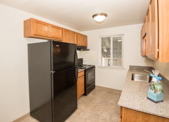 vacant apartment kitchen with black appliances and wood cabinets at Todd Village Apartments, Tualatin