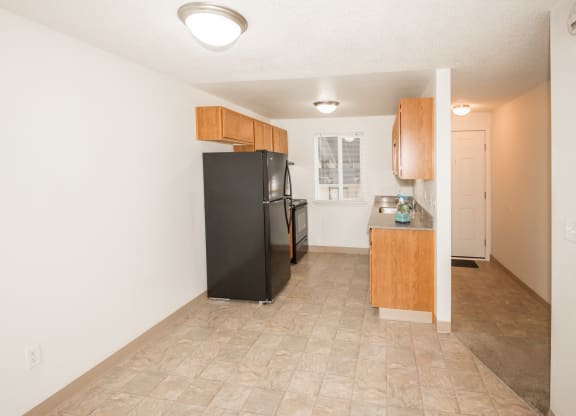 vacant apartment dining area and kitchen with black appliances and wood cabinets at Todd Village Apartments, Tualatin, 97062