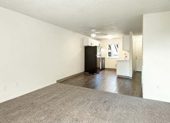 A black refrigerator is in a white room with a grey carpet at Todd Village Apartments, Oregon, 97062