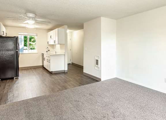 A kitchen with a black fridge and a living room with grey carpet at Todd Village Apartments, Oregon, 97062