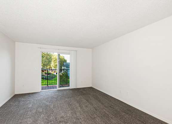 A room with a grey carpet and white walls with a sliding glass door at Todd Village Apartments, Oregon, 97062