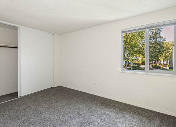 A room with a large window and a grey carpet at Todd Village Apartments, Oregon, 97062