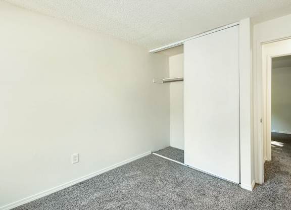 A room with a white wall and a white closet with a shelf at Todd Village Apartments, Oregon, 97062