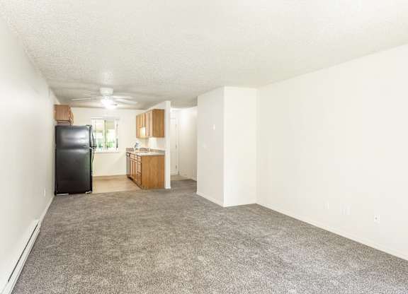 A room with a black fridge and wooden cabinets at Todd Village Apartments, Oregon, 97062