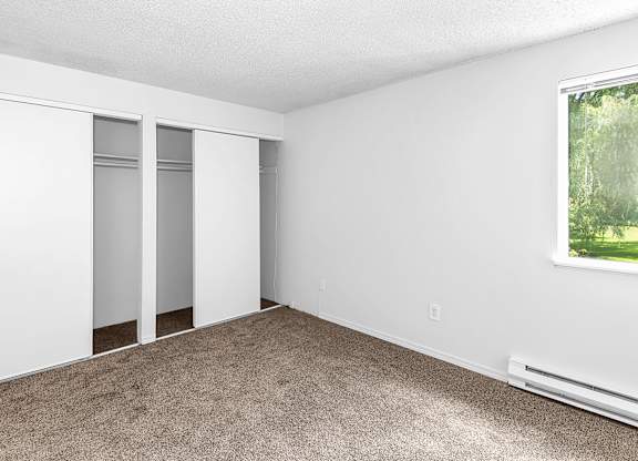 A room with a window, carpeted floor, and a white wall with a window at Todd Village Apartments, Oregon, 97062