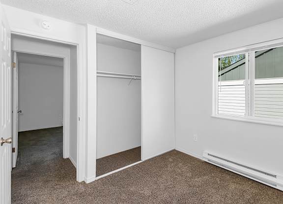 A white room with a window and a carpeted floor at Todd Village Apartments, Oregon, 97062