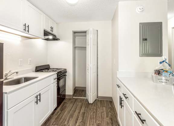 A kitchen with white cabinets and a wooden floor at Todd Village Apartments, Oregon, 97062
