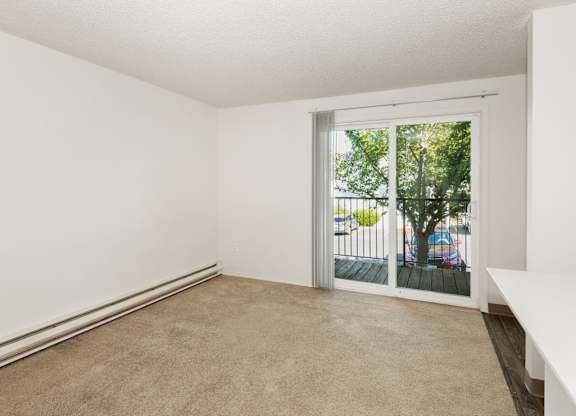 A room with a carpeted floor and a sliding glass door leading to a balcony at Todd Village Apartments, Oregon, 97062