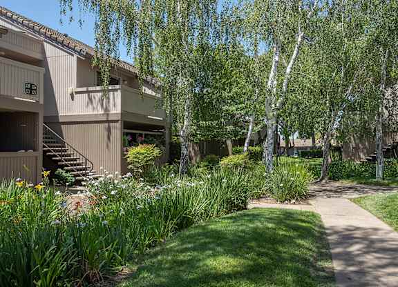 A pathway leads through a grassy area between two buildings at Zinfandel Village Apartments, California, 95670
