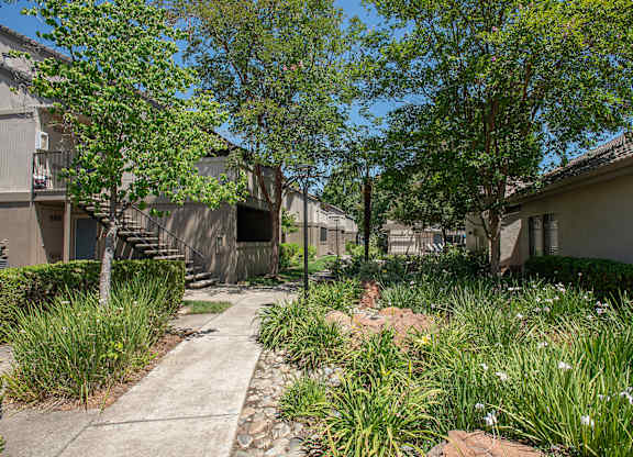 A pathway leads through a grassy area between two apartment buildings at Zinfandel Village Apartments, California, 95670