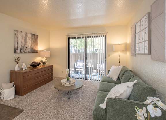 A living room with a green couch and a wooden dresser at Zinfandel Village Apartments, California, 95670