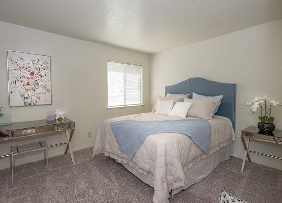 A bedroom with a bed, nightstand, and a painting on the wall at Zinfandel Village Apartments, California, 95670
