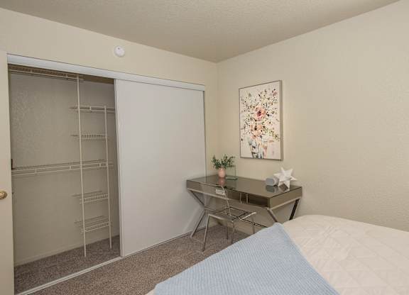 A bedroom with a bed, desk, chair, and a painting on the wall at Zinfandel Village Apartments, California, 95670