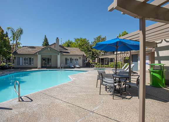 A pool with chairs and umbrellas at Zinfandel Village Apartments, California, 95670