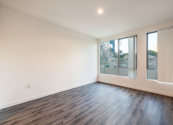 a living room with white walls and wood floors and a large window