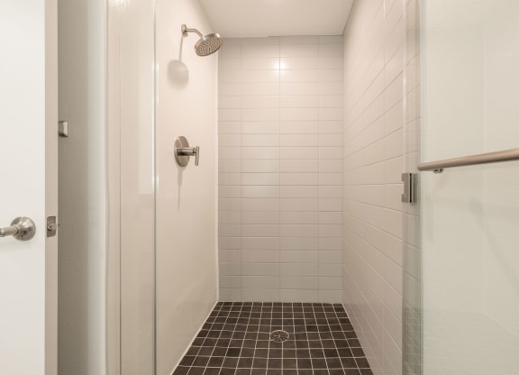 a tiled shower in a bathroom with a white door