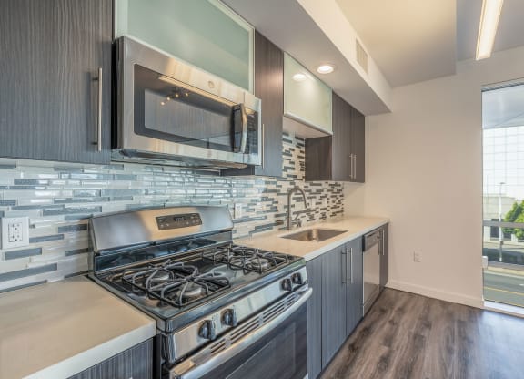 a kitchen with a stove and microwave and a sink