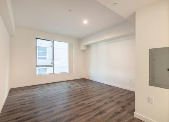an empty living room with wood flooring and a window