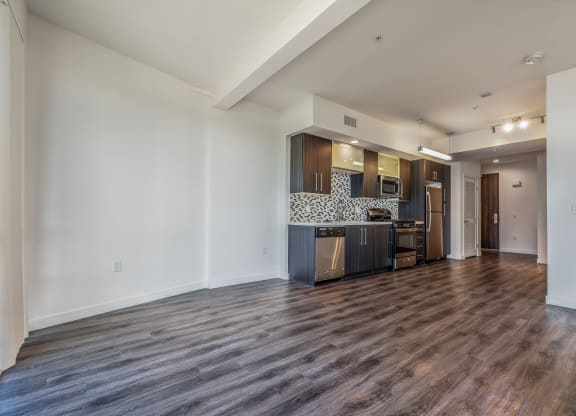 a living room and kitchen with a wood floor and white walls