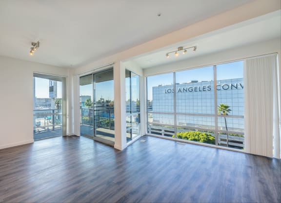 a living room with wood flooring and large windows and a balcony