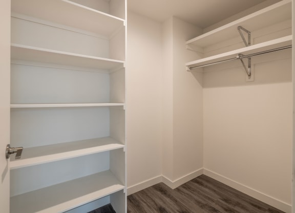 a walk in closet in a home with empty shelves