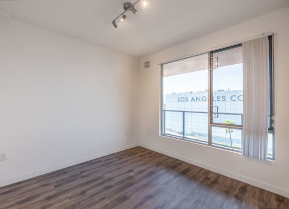 an empty living room with a large window and wood flooring