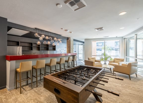 a clubhouse with a foosball table and a bar with chairs