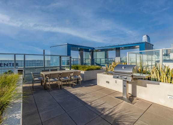 a patio with a barbecue grill and tables on a roof