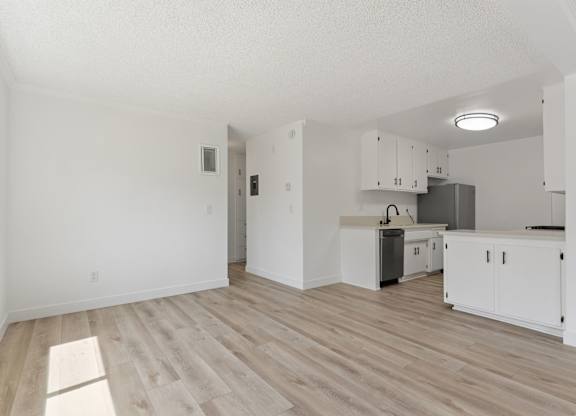 A kitchen with white cabinets and a wooden floor.