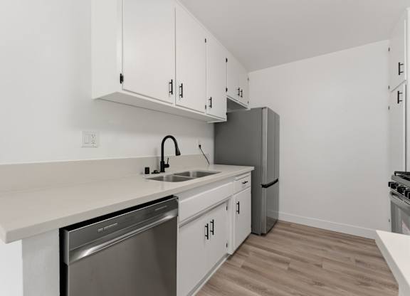 A kitchen with white cabinets and a stainless steel dishwasher.