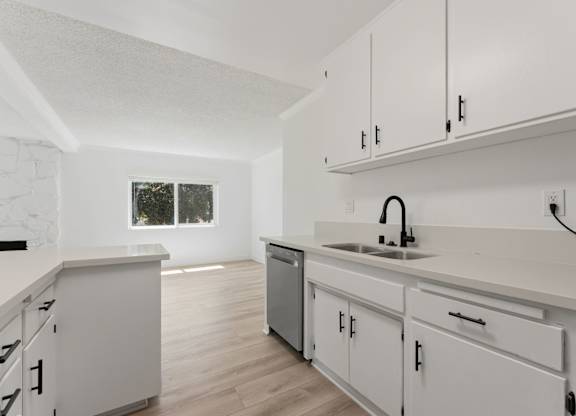 A kitchen with white cabinets and a window.