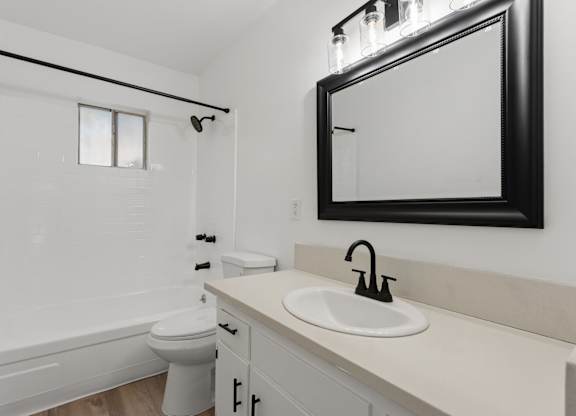 A white bathroom with a toilet, sink, and mirror.