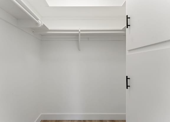 A white closet with a white door and a white shelf above it.