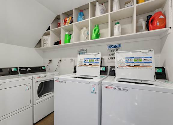 A laundry room with a washer and dryer and a shelf with cleaning supplies.