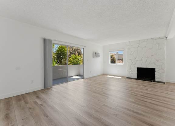 A room with a fireplace and a sliding glass door leading to a balcony.