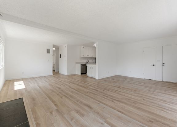 A spacious room with wooden flooring and white walls.