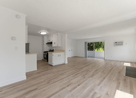 A spacious room with wooden flooring and white walls.