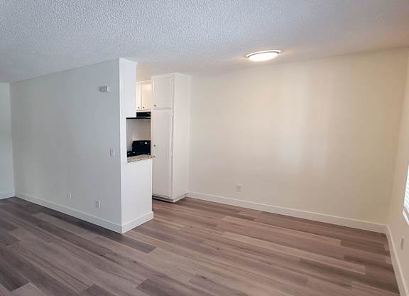 A room with wooden flooring and white walls.