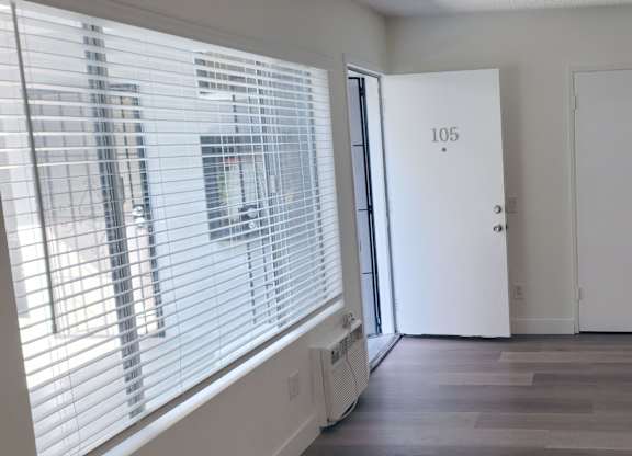 A room with a door marked 105 and a window with blinds.