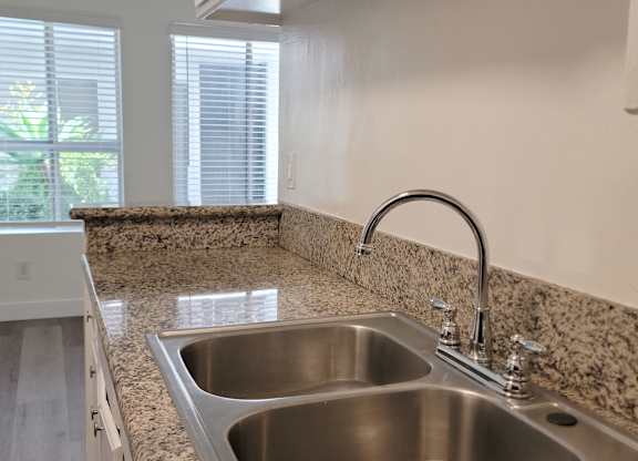 A kitchen with a granite countertop and a stainless steel sink.