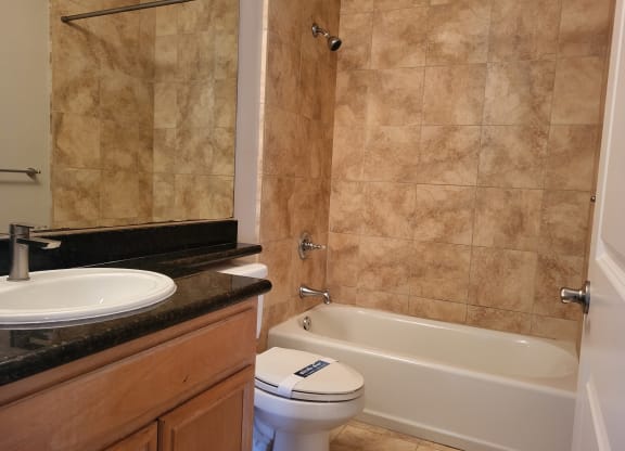 Elegant tile bathroom with white fixtures and granite counter top at The Cove at Bear Valley in Escondido, California.