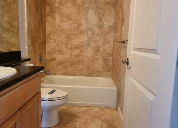 Bathroom with granite countertop and white fixtures at The Cove at Bear Valley in Escondido, California.