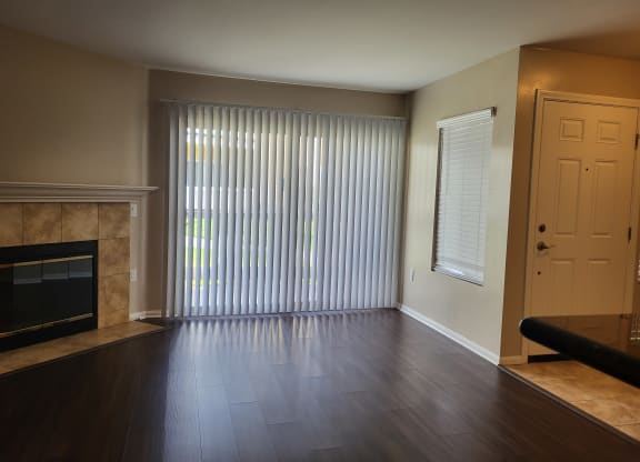 Living room with plank style flooring, beautiful fireplace and lots of windows at The Cove at Bear Valley in Escondido, California.