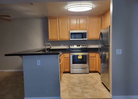 Open kitchen with granite counter tops, spacious wood cabinets, tile flooring, and stainless steel apliances at The Cove at Bear Valley in Escondido, California.