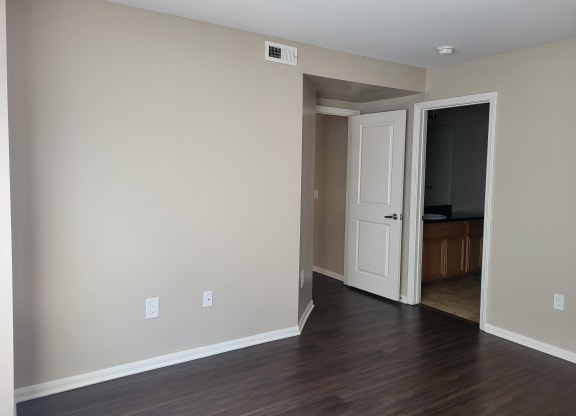 Master bedroom with plank style flooring, private bathroom and large walk-in closet at The Cove at Bear Valley in Escondido, California.